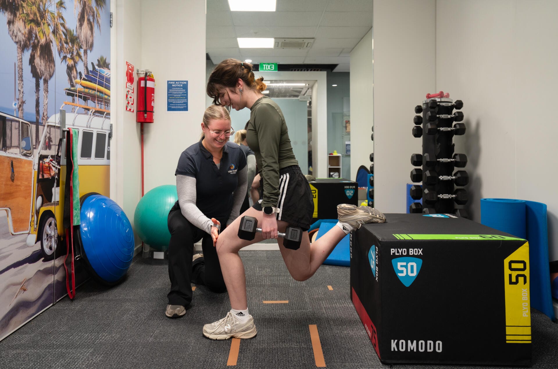Trainer assisting woman with dumbbell split squat